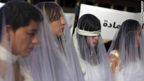 A dozen Lebanese women, dressed as brides in white wedding dresses stained with fake blood and bandaging their eyes, knees and hands stand in front of the government building in downtown Beirut, Lebanon, Tuesday, Dec. 6, 2016. The activists are protesting a Lebanese law that allows a rapist to get away with his crime if he marries the survivor. The law, in place since the late 1940s, is currently reviewed in Lebanese parliament. Campaigners against the law are calling on lawmakers to repeal the law during their meeting Wednesday. (AP Photo/Bilal Hussein)