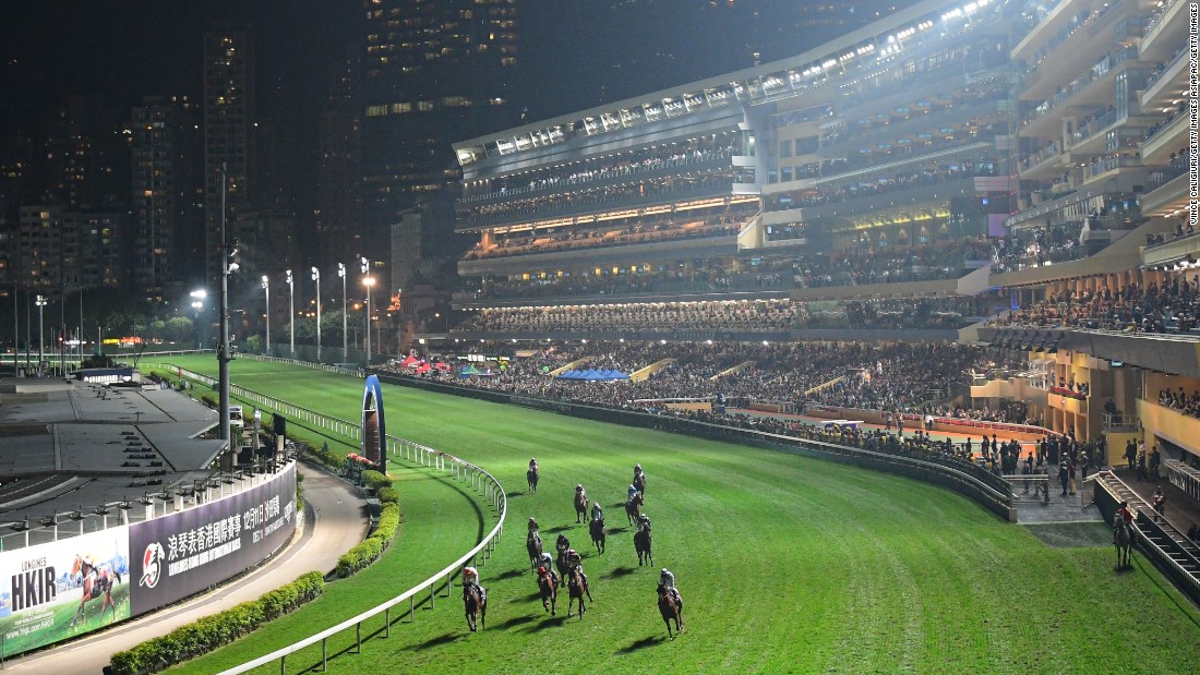 Competitors round the bend under the floodlights, with Hong Kong&#39;s skyline in the background.