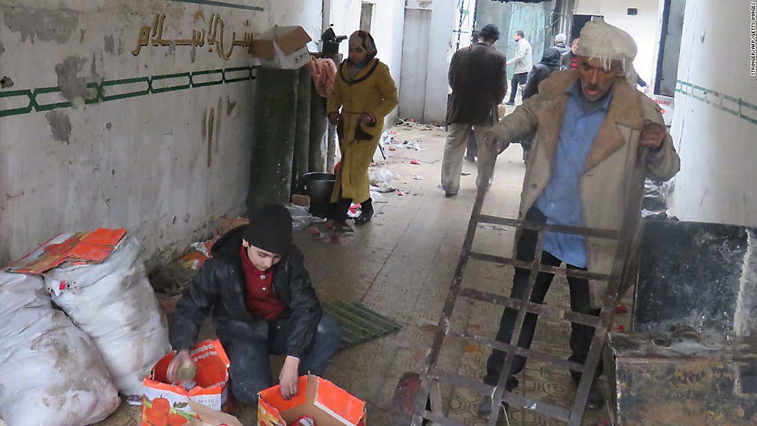 Syrian civilians take food from a storage room that was formerly held by the opposition forces in eastern Aleppo&#39;s al-Kalasseh neighborhood on December 13.