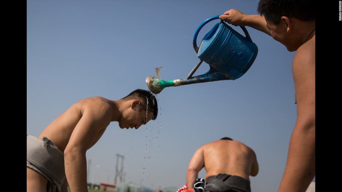A wrestler cools down a teammate during training.