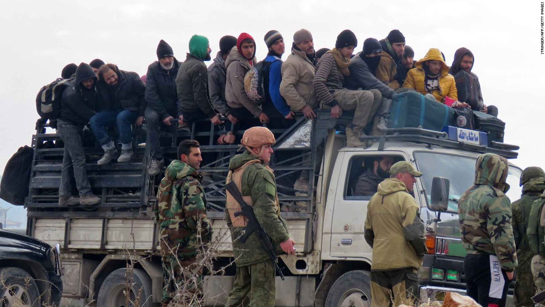 Russian soldiers and Syrian pro-government forces look on as civilians and rebel fighters are evacuated from Aleppo on Friday, December 16. Evacuations began a day earlier under a new ceasefire between rebels and pro-government forces.