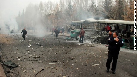 A police officer and people walking next to the wreck of public bus following an explosion on December 17, 2016 in Kayseri, central Turkey.