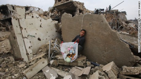 A boy sits with his belongings where his house once stood in Aleppo on December 17, 2016.