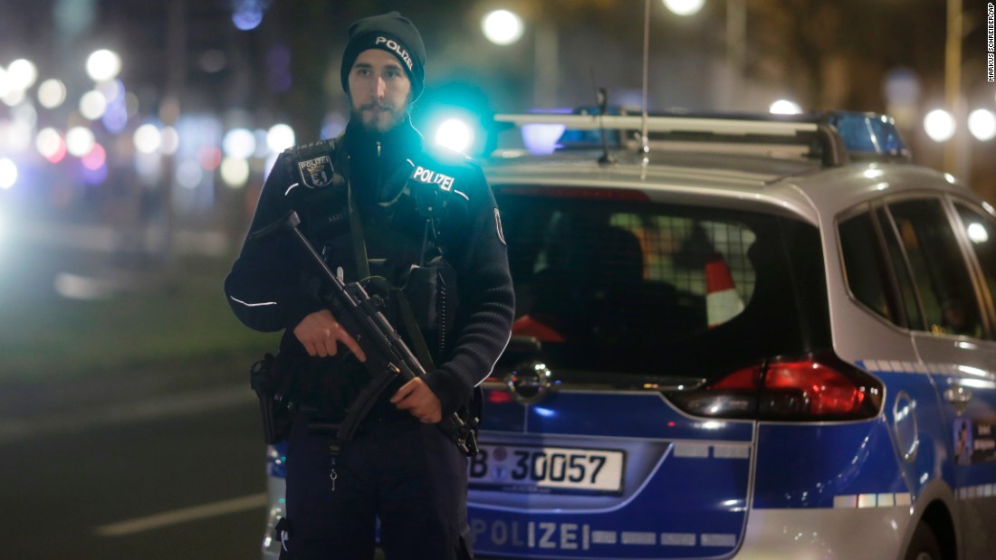 An armed police officer stands near the scene.