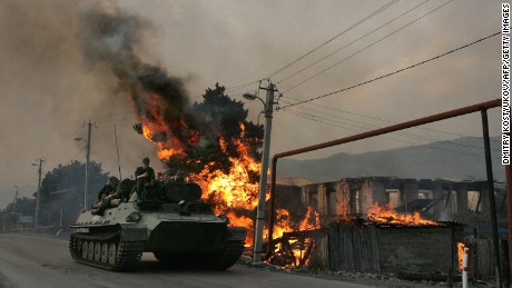 A Russian armoured vehicle passes a house set on fire by seperatist militia during the conflict between  Georgia and Russia, on August 18, 2008.