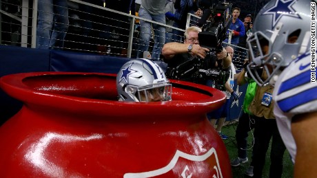 The Dallas Cowboys&#39; Ezekiel Elliott celebrates in a Salvation Army kettle after scoring a touchdown Sunday.