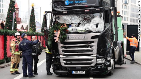 A policeman and firemen stand next to a truck on December 20, 2016 at the scene where it crashed into a Christmas market near the Kaiser-Wilhelm-Gedaechtniskirche (Kaiser Wilhelm Memorial Church) in Berlin.
German police said they were treating as &quot;a probable terrorist attack&quot; the killing of 12 people when the speeding lorry cut a bloody swath through the packed Berlin Christmas market.