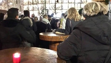 Mourners gather around tables at the closed Christmas market to listen to the service inside the Memorial Church.