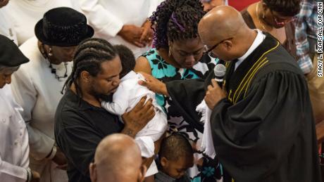 The Rev. Eric S.C. Manning prays with a couple baptizing their son in 2016.