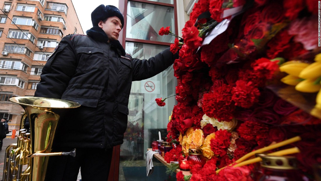 A Russian police orchestra musician places a flower in tribute to members of the Alexandrov Ensemble outside their home stage building in Moscow on December 26. The popular ensemble was scheduled to perform for Russian pilots in Syria ahead of New Year&#39;s Day.