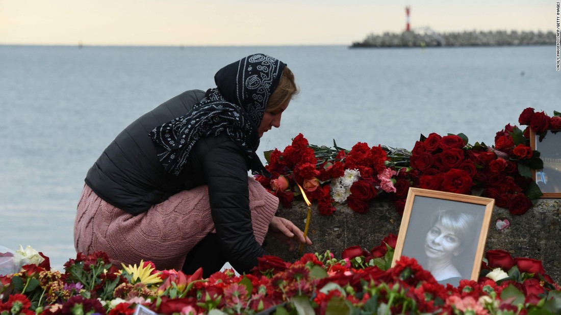 A woman lights a candle Tuesday next to makeshift memorial in Sochi, Russia, for  Russian activist Elizaveta Glinka, who was killed in the crash. Also presumed dead were nine journalists and more than 60 members of the Russian army&#39;s official choir, the Alexandrov Ensemble.