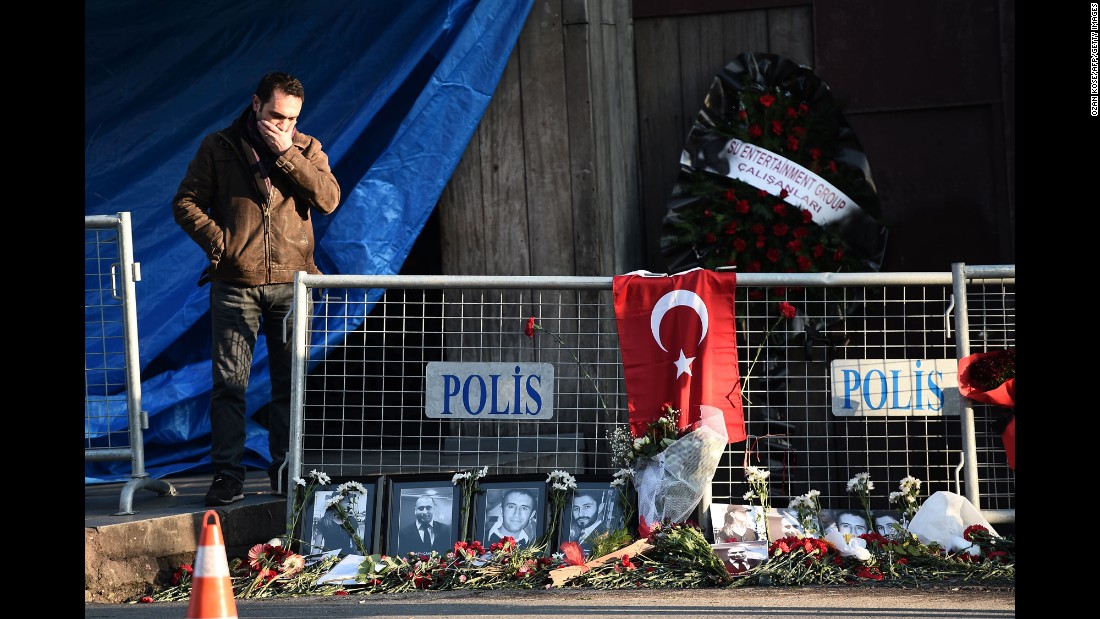 A friend of someone killed in the attack reacts near victims&#39; pictures outside the nightclub on January 2.