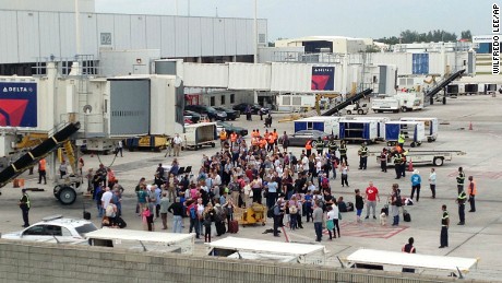People stand on the tarmac at the Fort Lauderdale-Hollywood International Airport after a shooter opened fire inside a terminal of the airport, killing several people and wounding others before being taken into custody, Friday, January 6 in Fort Lauderdale, Florida.