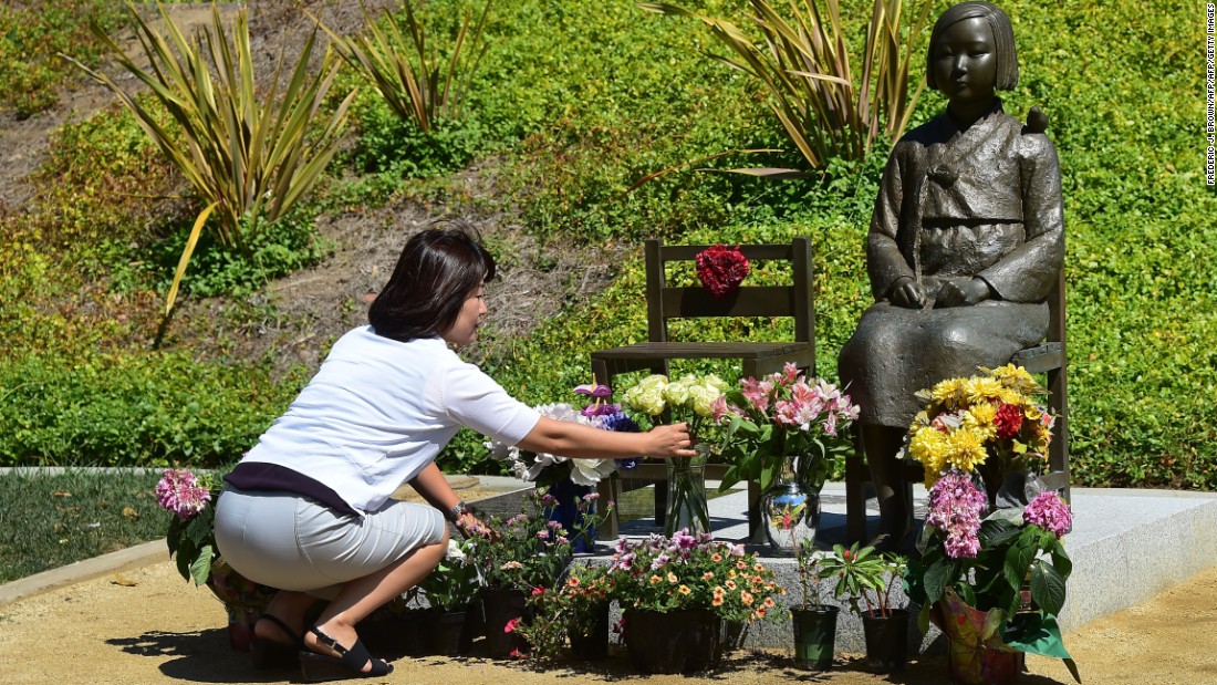 A woman arranges flowers in front of a &quot;comfort woman&quot; statue in Glendale, California. 