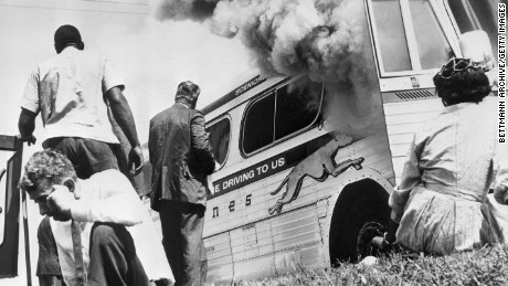 Passengers of this smoking Greyhound bus, some of the members of the &quot;Freedom Riders,&quot; a group sponsored by the Congress of Racial Equality (CORE), sit on the ground after the bus was set afire 5/14/1961, by a mob of Caucasians who followed the bus from the city. The mob met the bus at the terminal, stoned it &amp; slashed the tires, then followed the bus from town. 
