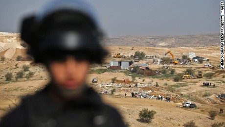 An Israeli officer on guard as bulldozers demolish homes in the Bedouin village of Umm al-Hiran.