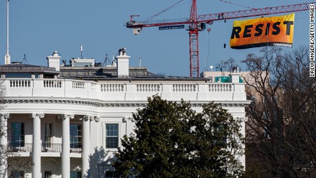 WASHINGTON, DC - JANUARY 25: With the White House in the foreground, protesters unfurl a banner atop a crane at the construction site of the former Washington Post office building, January 25, 2017 in Washington, DC. The protestors are with the Greenpeace organization.