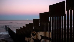 A supermoon sets at the US-Mexico border fence in November 2016.