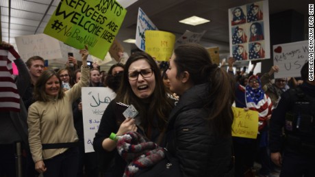 A detained traveler reacts after being cleared through