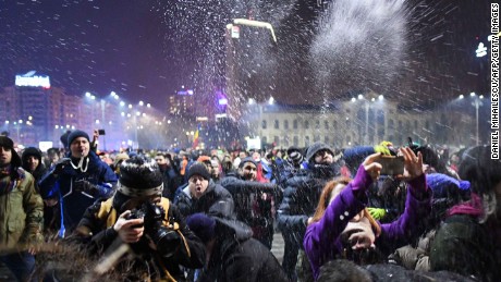 People throw snow toward  police guarding government headquarters in Bucharest.