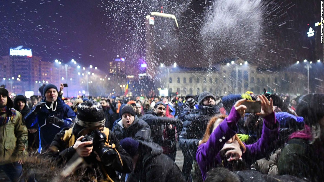 People throw snow at police protecting government headquarters on January 31 in Bucharest. Protesters also took to the streets in other cities across Romania.