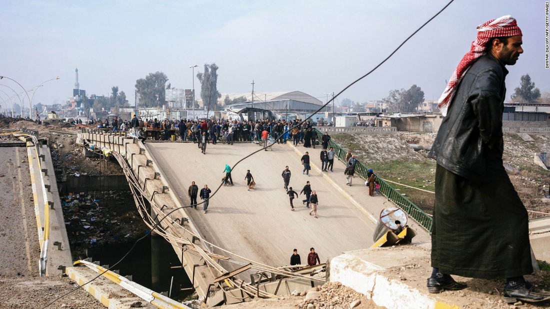 Mosul residents cross a damaged bridge in the al-Sukkar neighborhood on Saturday, January 21.