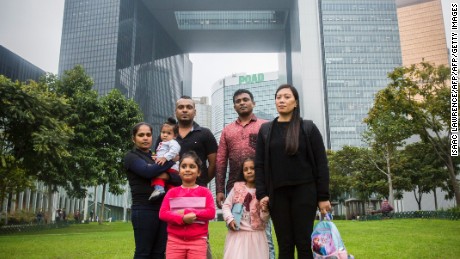 Sri Lankan refugee Supun Thilina Kellapatha (third from left), his partner Nadeeka (left), with their baby boy Dinath, daughter Sethumdi, Sri Lankan refugee Ajith Puspa (third from right),and Filipino refugee Vanessa Rodel (right) with her daughter Keana pose for a photo in front of the government buildings of Hong Kong in 2017.