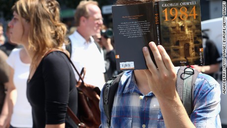 BERLIN, GERMANY - AUGUST 01:  A protester holds a German translation of George Orwell's book '1984' as he demonstrates for journalists' rights on August 1, 2015 in Berlin, Germany. After two German journalists, Andre Meister and Markus Beckedahl, reported that the German government planned to increase online surveillance, an investigation for treason, the first such case in the country against journalists in over 50 years, was brought against them and has since been suspended by the country's prosecutor-general after negative reactions from other journalists and politicians due to the implications of stifling the freedom of the press.  (Photo by Adam Berry/Getty Images)