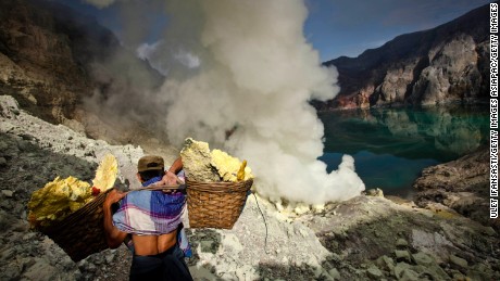 BANYUWANGI, EAST JAVA - DECEMBER 17:  A miner carries sulfur during an annual offering ceremony on the Ijen volcano on December 17, 2013 in Banyuwangi, Indonesia.  The ritual is performed by the sulfur miners of Mount Ijen who slaughter a goat and then bury the head in the crater of mount Ijenn. The sacrifice is performed to ward off potential disasters for the next year. The Ijen crater rises to 2,386m, with a depth of over 175m, making it one of the world&#39;s largest craters. Sulphur mining is a major industry in the region, made possible by an active vent at the edge of a lake, but the work is not without risks as the acidity of the water in the crater is high enough to dissolve clothing and cause breathing problems. (Photo by Ulet Ifansasti/Getty Images)
