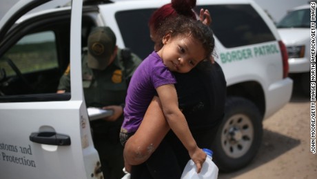 A mother and her 3-year-old child from El Salvador await transport to an immigrant processing center after they crossed the Rio Grande into the United States on July 24, 2014.