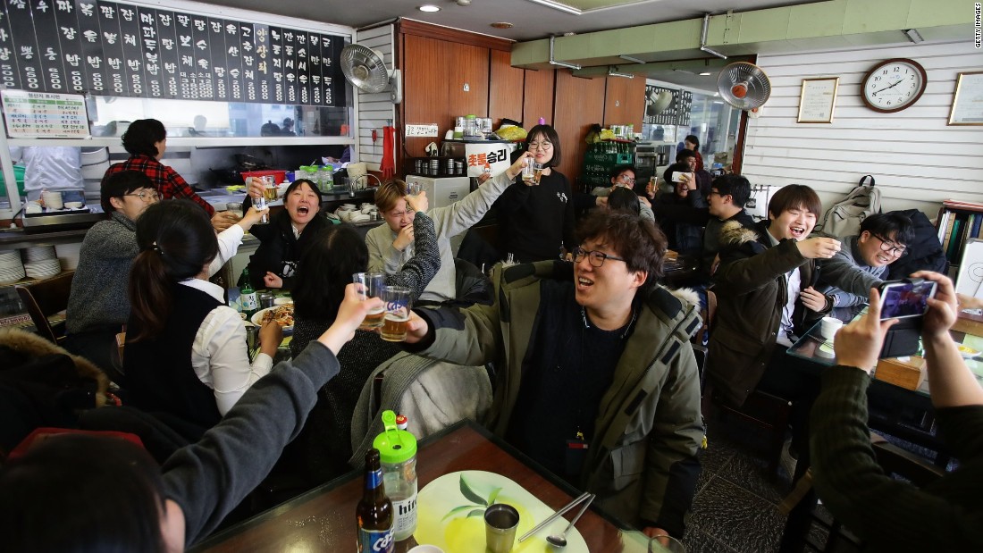 South Koreans celebrate at a restaurant after hearing the court&#39;s unanimous verdict.