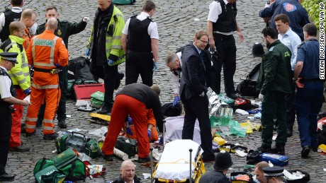 Conservative MP Tobias Ellwood, centre, stands amongst the emergency services at the scene outside the Palace of Westminster, London, Wednesday, March 22, 2017.  London police say they are treating a gun and knife incident at Britain's Parliament "as a terrorist incident until we know otherwise." The Metropolitan Police says in a statement that the incident is ongoing. It is urging people to stay away from the area. Officials say a man with a knife attacked a police officer at Parliament and was shot by officers. Nearby, witnesses say a vehicle struck several people on the Westminster Bridge.  (Stefan Rousseau/PA via AP).