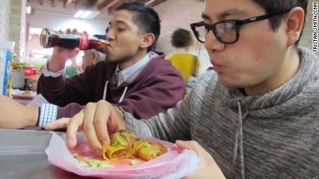 Matadamas, left, and his cousin, Daniel Velasco,  eating at a taco stand.                            