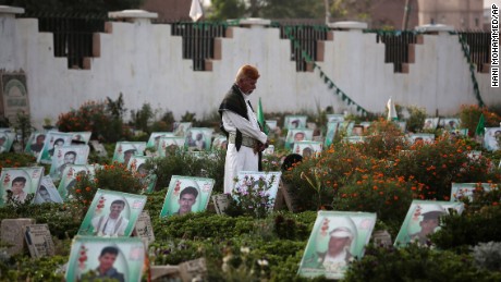 A Yemeni man offers prayers at the portrait adorned grave of his relative who was killed in the ongoing conflict in Yemen, at cemetery in Sanaa. 