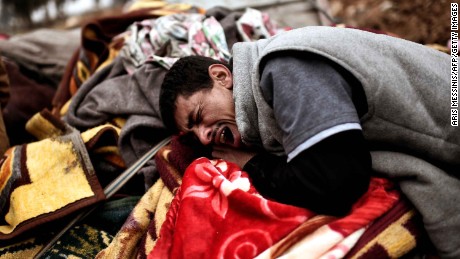 TOPSHOT - Relatives mourn as bodies of Iraqi residents of west Mosul killed in an airstrike targeting Islamic State (IS) group jihadists are placed and covered with blankets on carts on March 17, 2017. / AFP PHOTO / ARIS MESSINIS        (Photo credit should read ARIS MESSINIS/AFP/Getty Images)