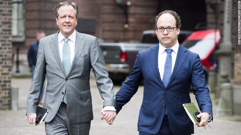 Men hold hands in solidarity with gay couple