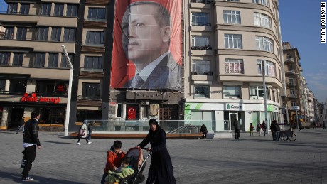 Istanbul residents walk past Erdogan&#39;s &quot;Yes&quot; campaign banner in Istanbul&#39;s Taksim Square on Sunday.