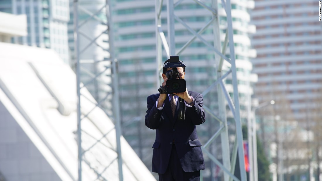 Foreign journalists are filmed by North Korean media during the Ryomyong Street event.