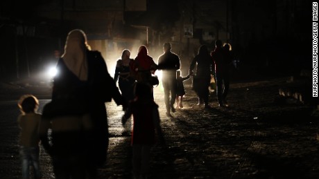 Gazans walk along a darkened street during a power outage on April 14.