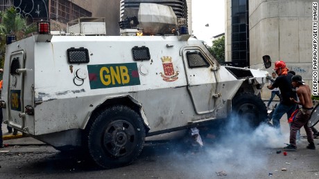 Yaminne, his head covered in a white rag, sits up after being run over by a security vehicle. 