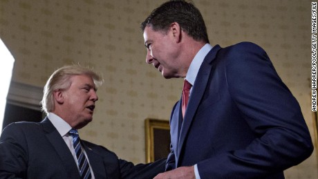 WASHINGTON, DC - JANUARY 22: U.S. President Donald Trump (C) shakes hands with James Comey, director of the Federal Bureau of Investigation (FBI), during an Inaugural Law Enforcement Officers and First Responders Reception in the Blue Room of the White House on January 22, 2017 in Washington, DC. Trump today mocked protesters who gathered for large demonstrations across the U.S. and the world on Saturday to signal discontent with his leadership, but later offered a more conciliatory tone, saying he recognized such marches as a &quot;hallmark of our democracy.&quot; (Photo by Andrew Harrer-Pool/Getty Images)