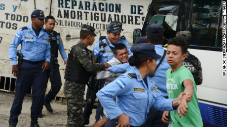 Police hold a boy whose father was killed in 2016 by alleged gang members for refusing to pay them a &quot;war tax&quot; in Tegucigalpa, Honduras.