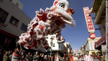 SAN FRANCISCO - JANUARY 29:  People watch a traditional lion dance in front of a bank on the first day of Chinese New Year on January 29, 2006 in Chinatown, San Francisco, California. The Lunar New Year celebration, which ushered in the Year of the Dog at midnight will last  for 3 days bringing families together to share food and pray at temples for good health and prosperity in the coming year. (Photo by David Paul Morris/Getty Images)