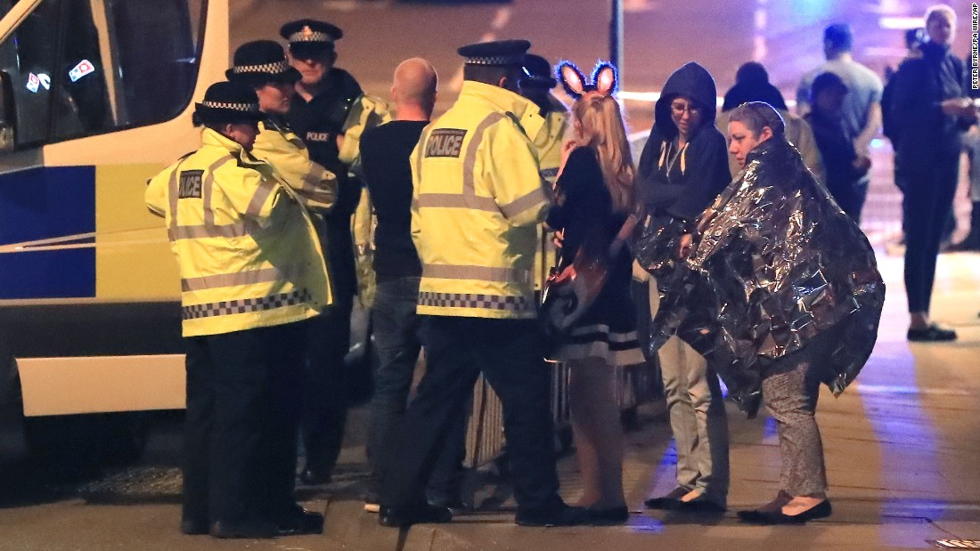 Emergency workers and concert attendees gather outside the arena.