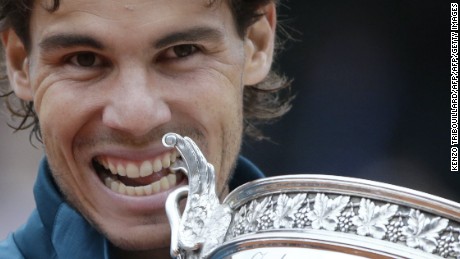 Spain&#39;s Rafael Nadal bites the Musketeers trophy after winning the 2013 French tennis Open final against Spain&#39;s David Ferrer at the Roland Garros stadium in Paris on June 9, 2013. AFP PHOTO / KENZO TRIBOUILLARD        (Photo credit should read KENZO TRIBOUILLARD/AFP/Getty Images)