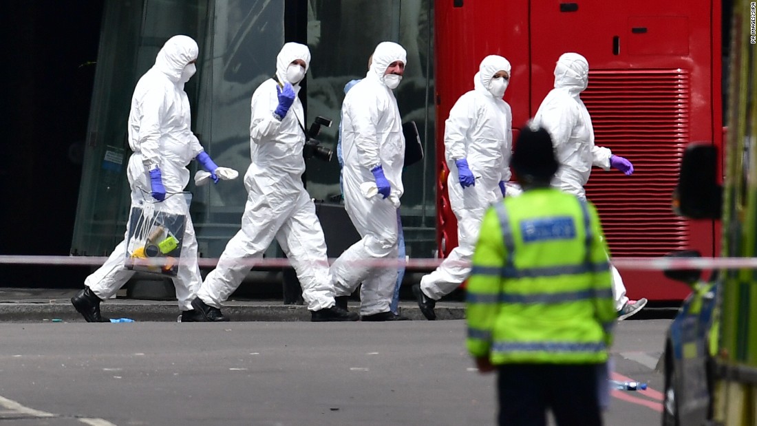 A group of police forensic officers walks in the street outside Borough Market.