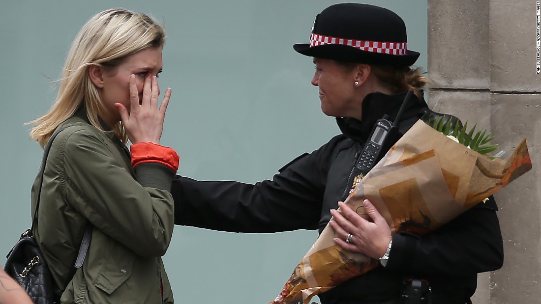 A woman reacts after asking a Police officer to lay flowers near London Bridge as a tribute to the victims of the attack.