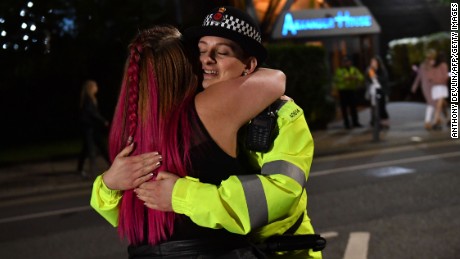 A music fan hugs a police officer as fans leave Old Trafford Cricket Ground following the One Love Manchester benefit concert for the families of the victims of the May 22, Manchester terror attack, in Greater Manchester on June 4, 2017. / AFP PHOTO / Anthony Devlin        (Photo credit should read ANTHONY DEVLIN/AFP/Getty Images)