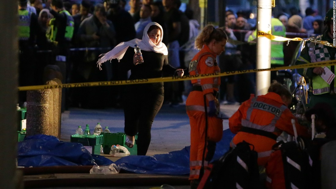 A woman runs near paramedics working near the fire.