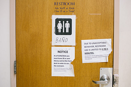 A notice on the bathroom door informs patrons of rules to use the bathroom at McPherson Square Library.